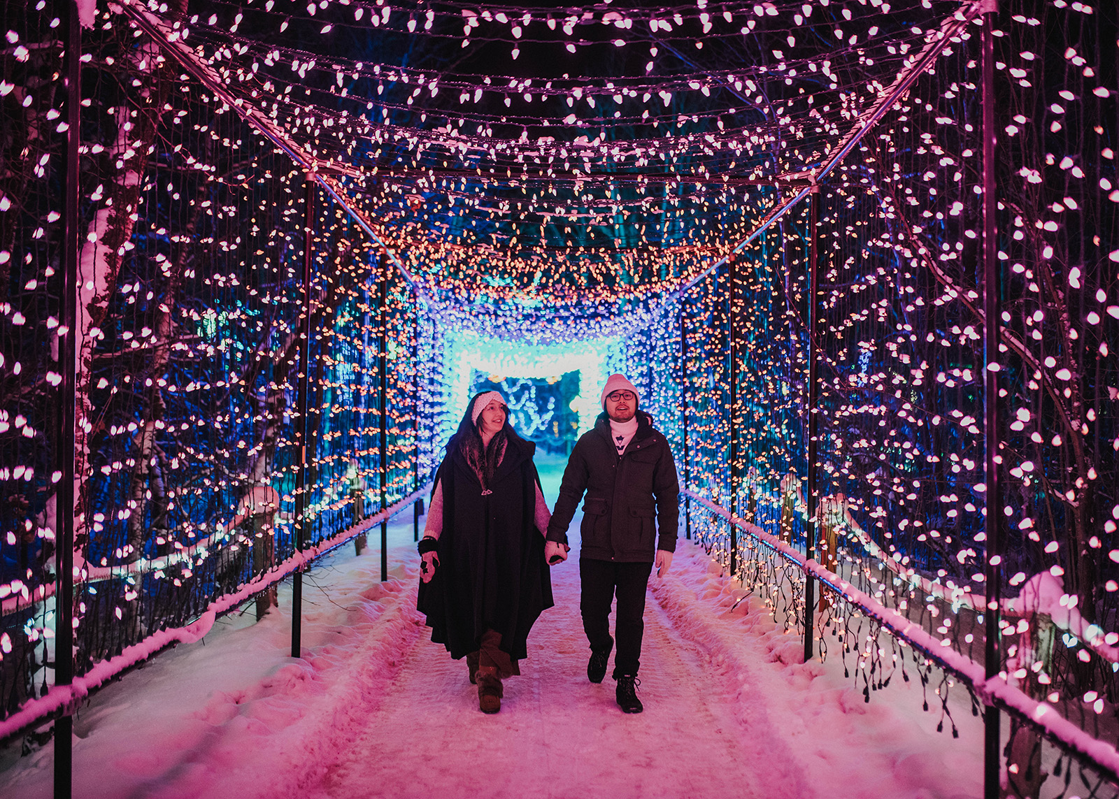 A couple walks hand in hand through a light tunnel